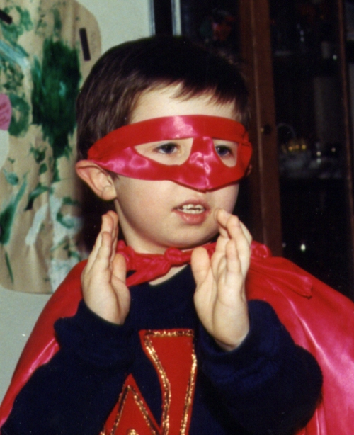 Preparing to fly in a red satin mask, a dark blue sweater (with a red letter across the chest) and a red satin cape